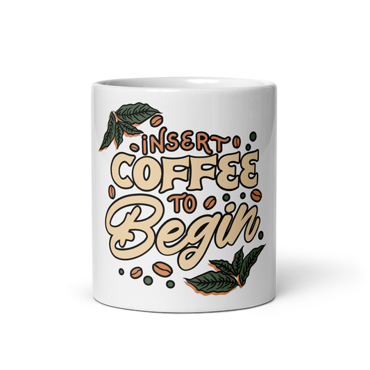 A white ceramic coffee mug featuring a hand-drawn style graphic that reads 'INSERT COFFEE TO Begin' in beige and brown lettering, decorated with coffee beans and green leaves, on a white background.