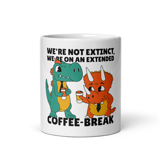 A white ceramic coffee mug featuring a cartoon graphic of two dinosaurs holding coffee cups, with the text 'WE'RE NOT EXTINCT, WE'RE ON AN EXTENDED COFFEE-BREAK'.